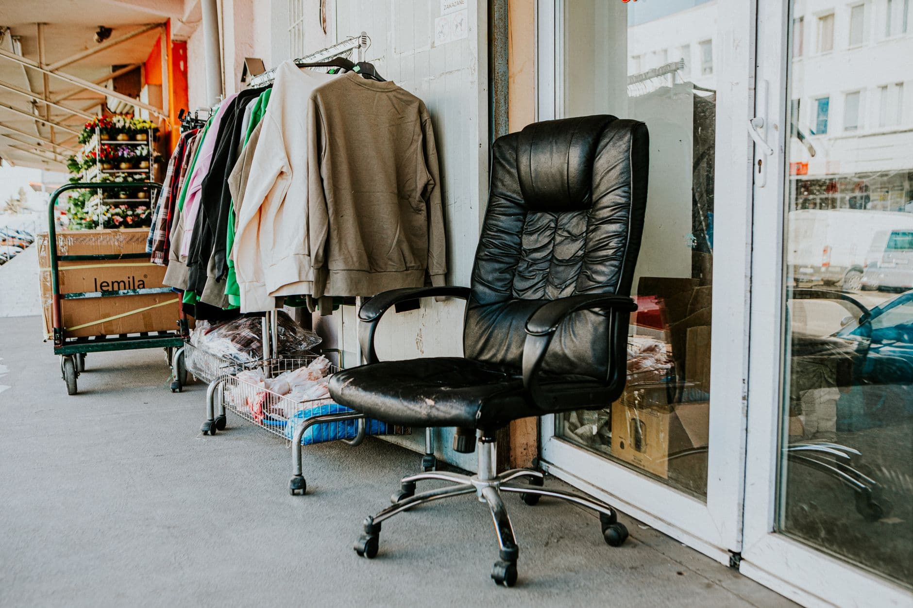 A worn black office chair left outside a secondhand store