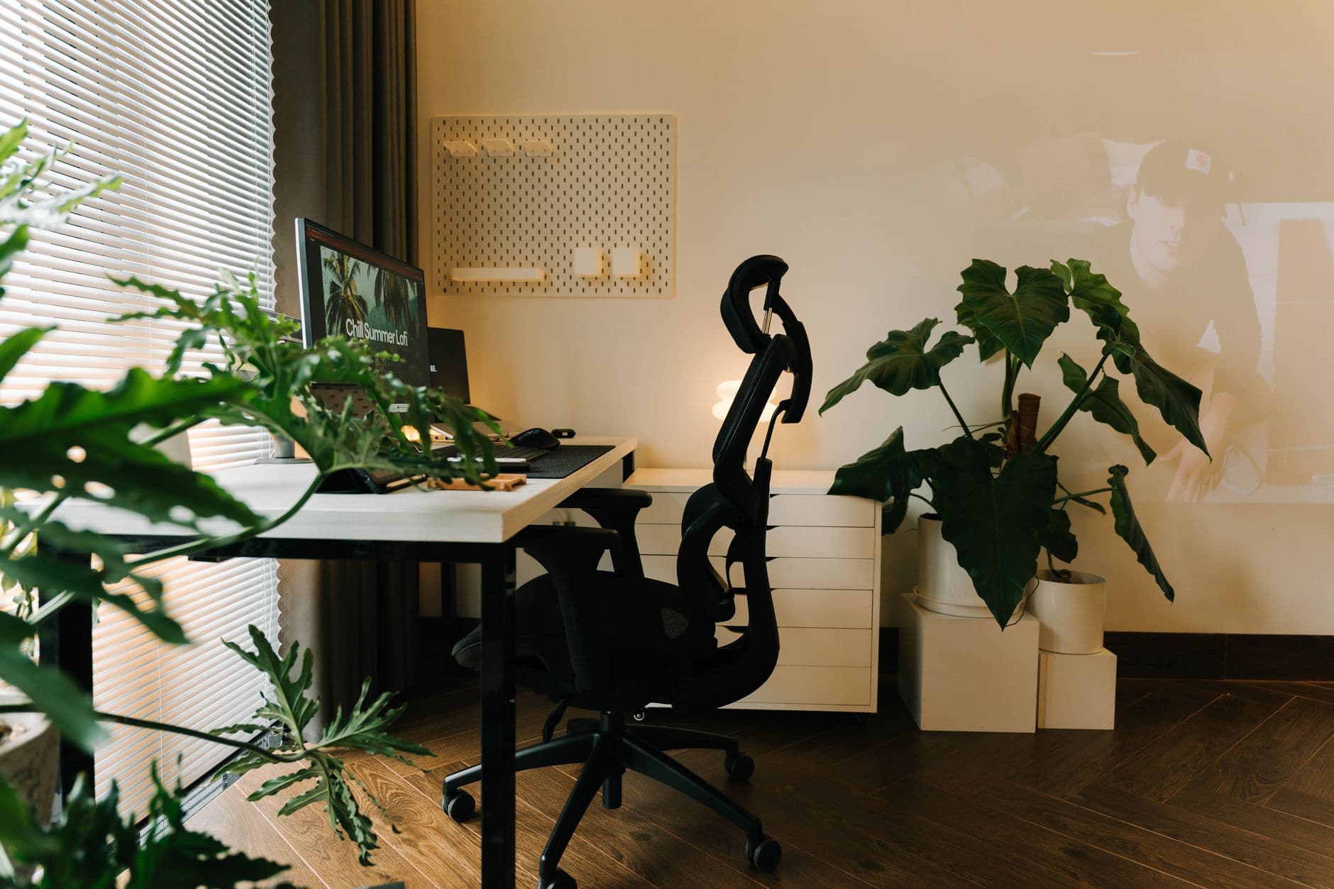 A home office with an ergonomic chair and plants beside a desk