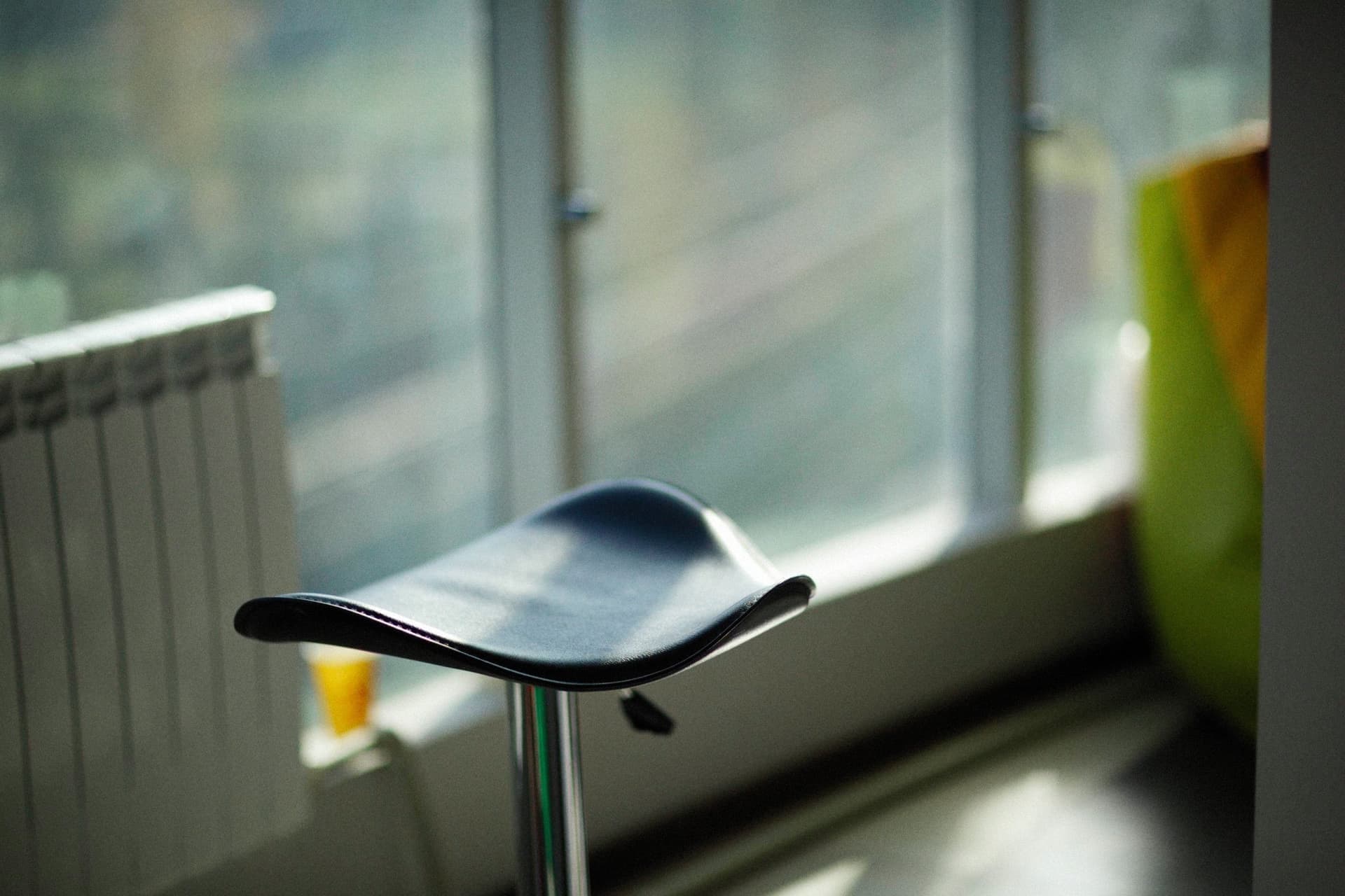 A perching stool with a tilted seat pad