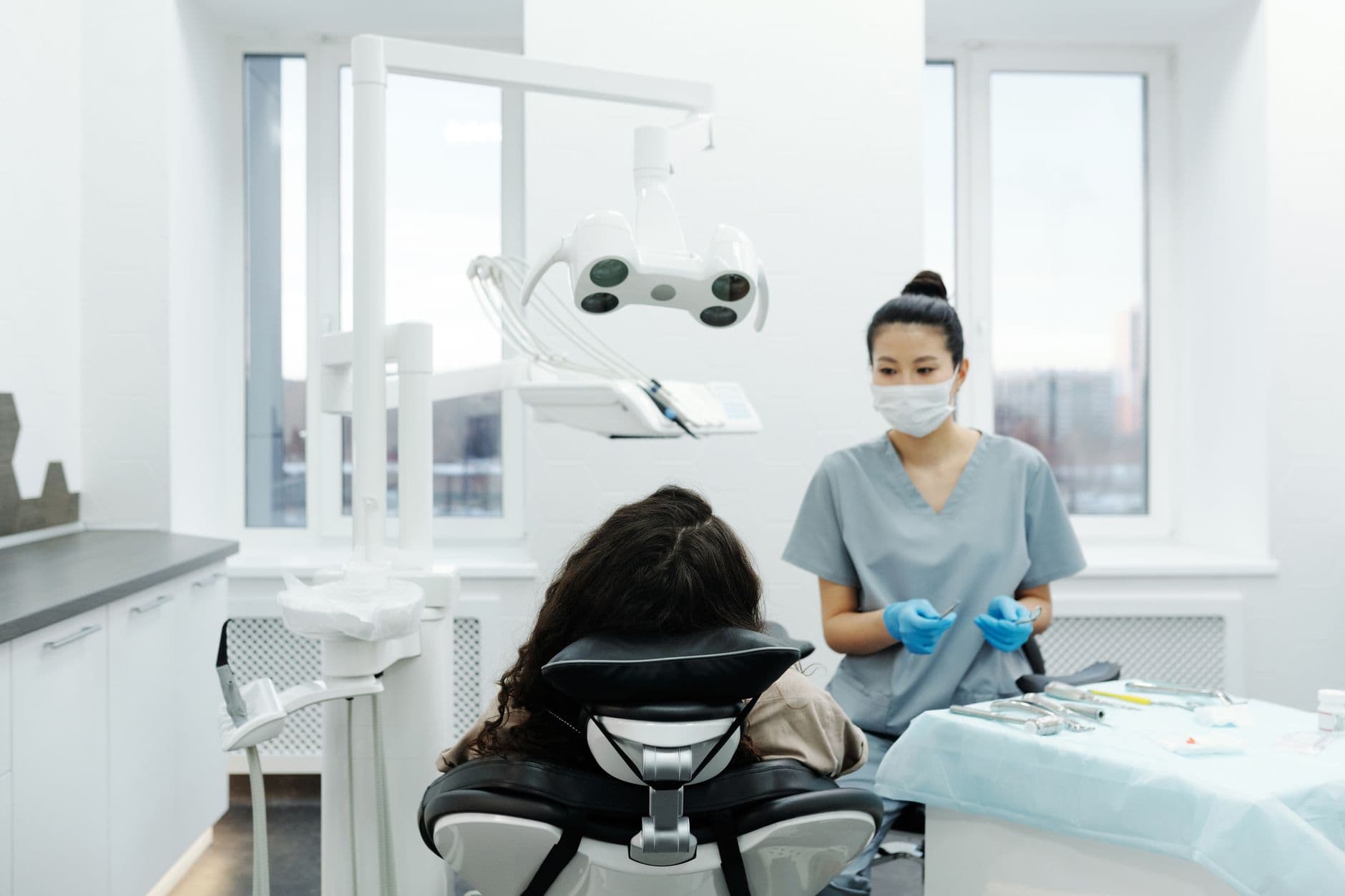A dentist seated at a patient chair in a modern clinic