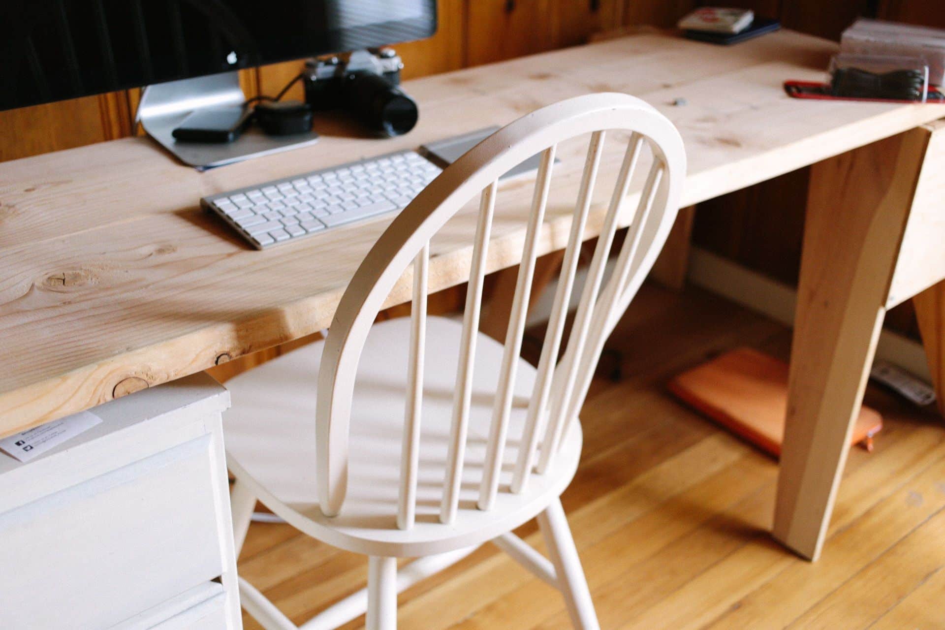 A wide-seated cross-legged office chair with flip-up armrests beside a desk