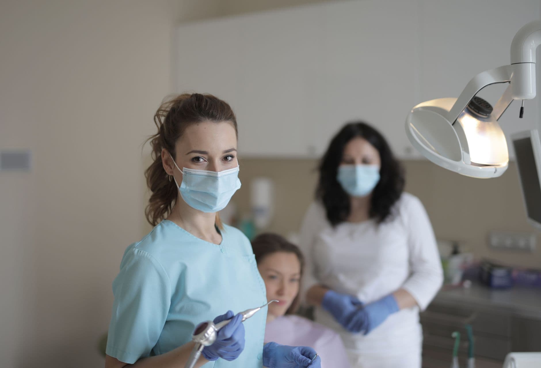 Two dentists in masks and gloves treating a patient in a modern dental surgery