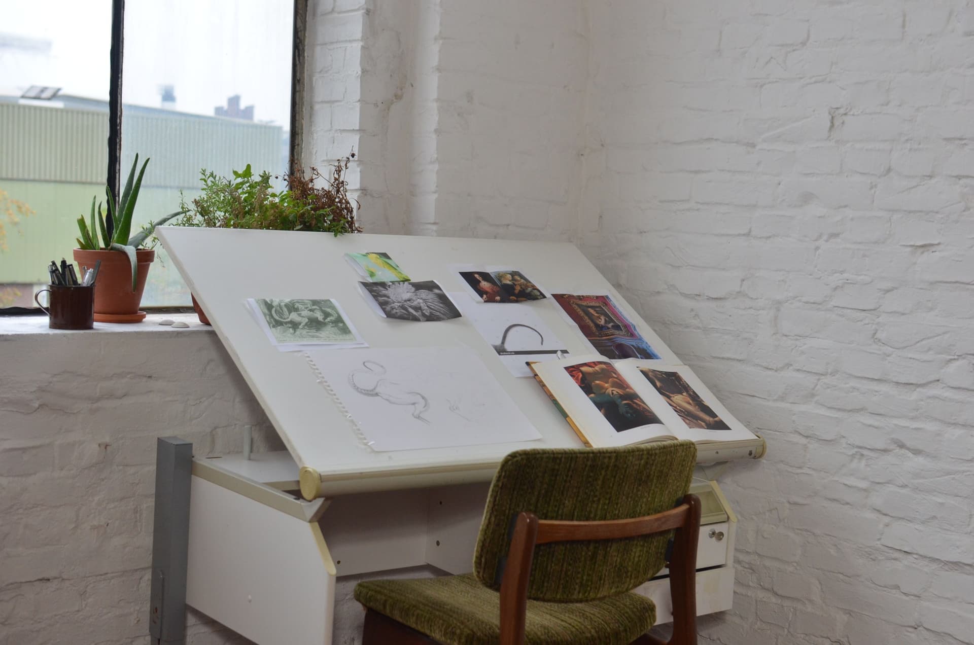 A tall drafting chair with a chrome foot ring at a standing-height desk