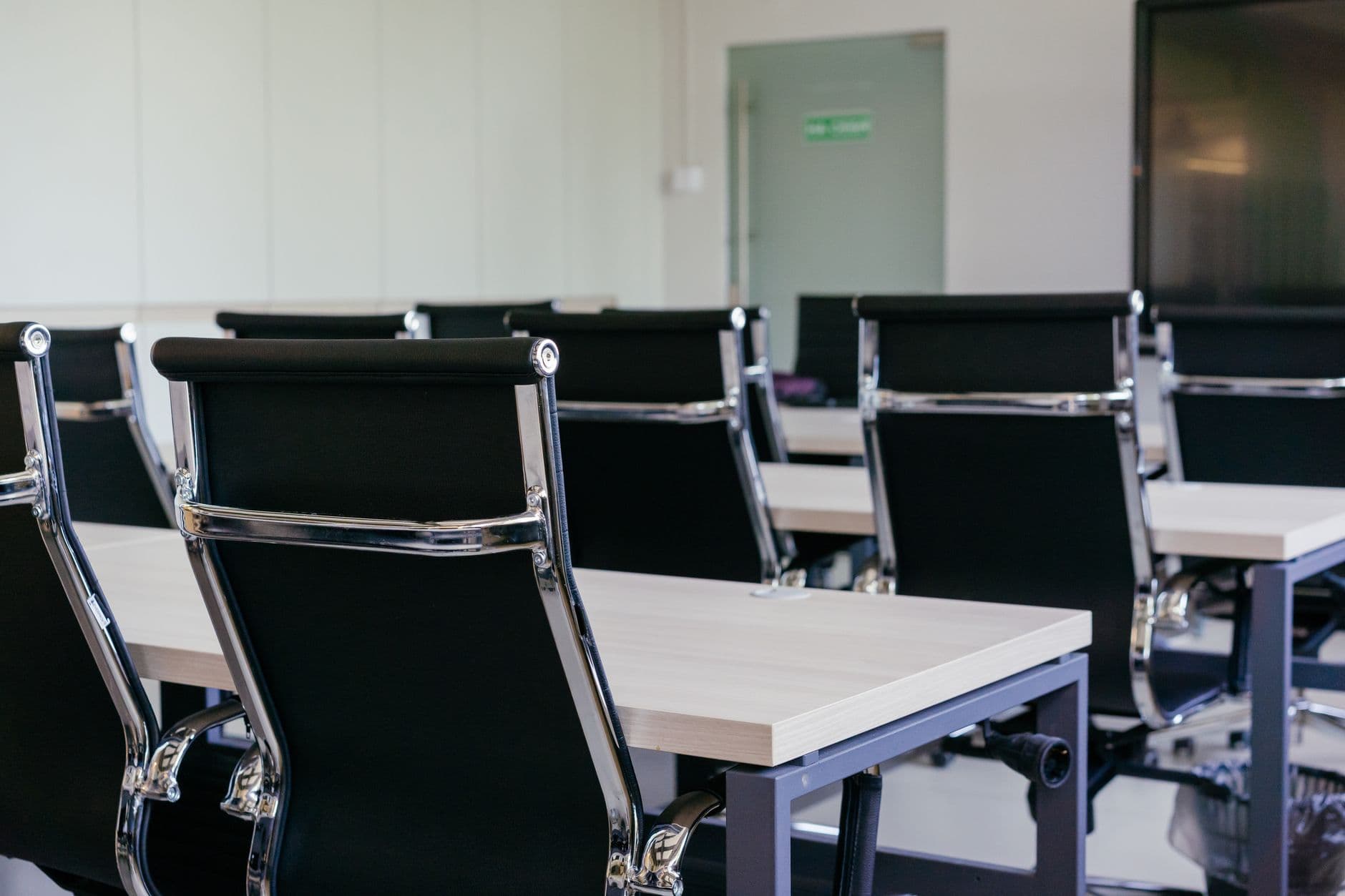 A modern meeting room with black task chairs at white desks