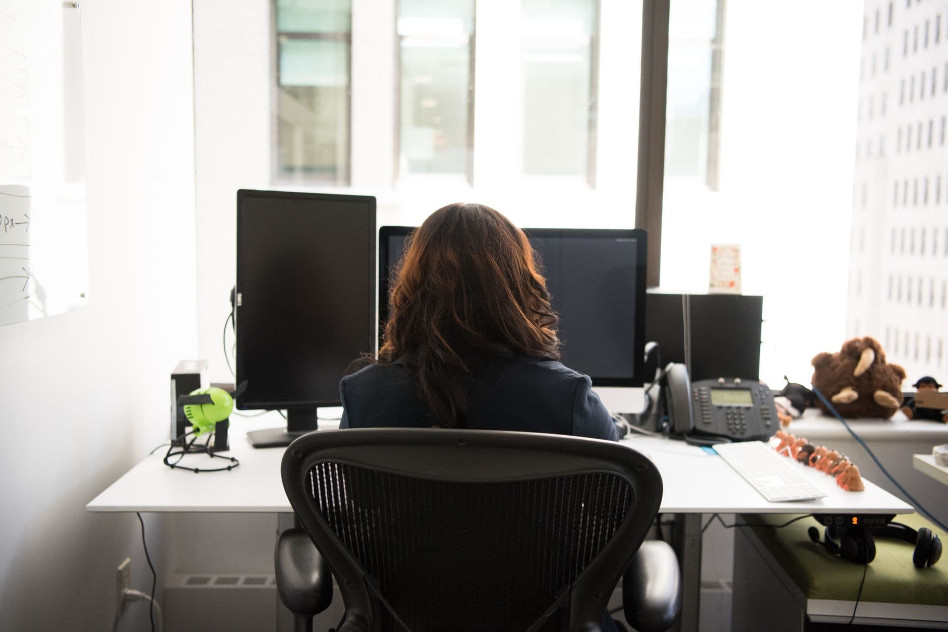 A person working at a desktop computer in a high-backed rolling office chair