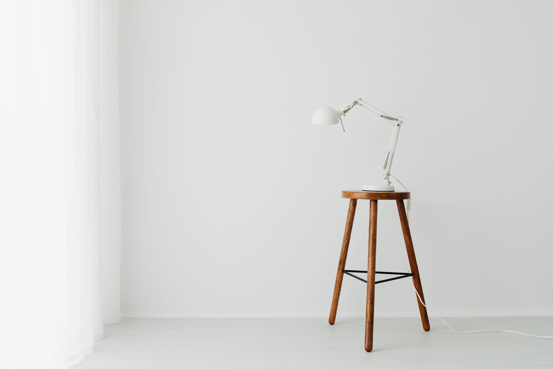 A leaning stool with a tilted seat pad beside a standing-height desk
