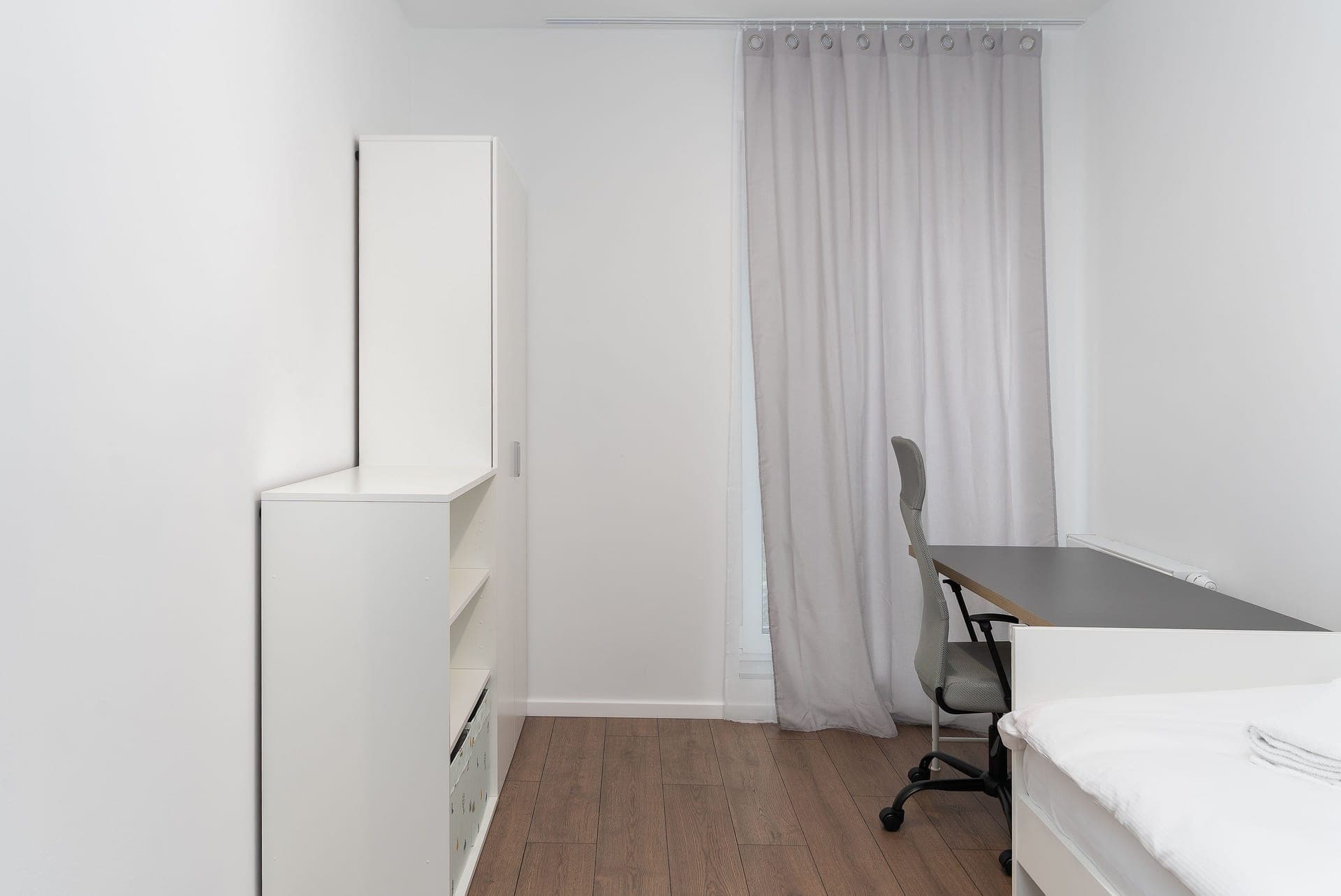A compact mid-back office chair with a short seat pan at a desk