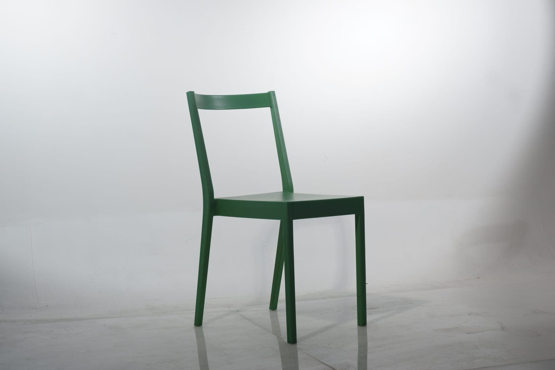 An ergonomic chair and a stool photographed against a plain wall
